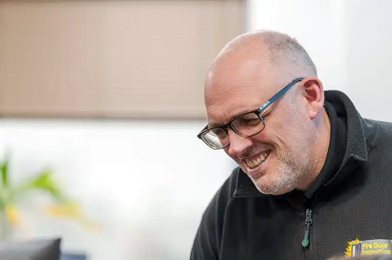 man with glasses smiling looking at computer screen