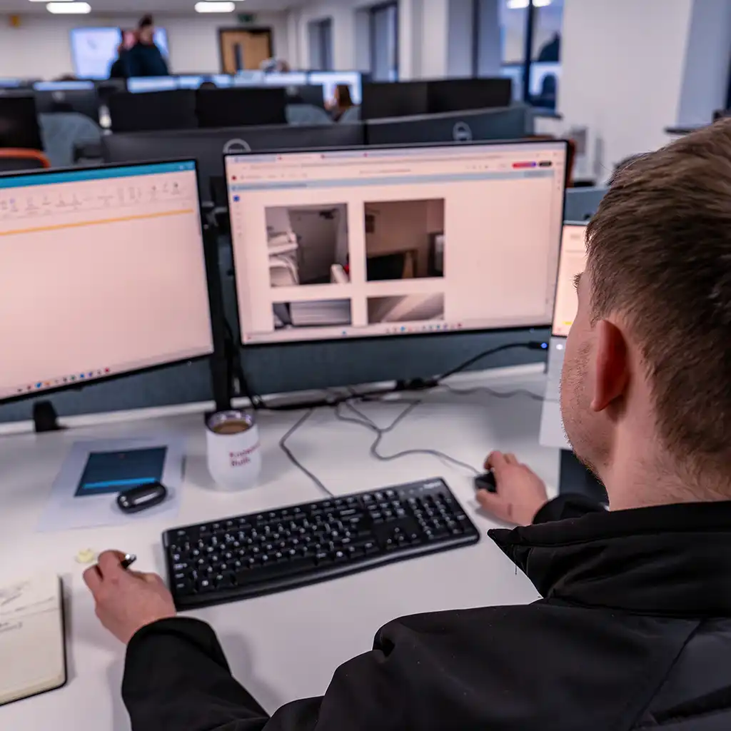 Compliance inspector checking work at two computer screens