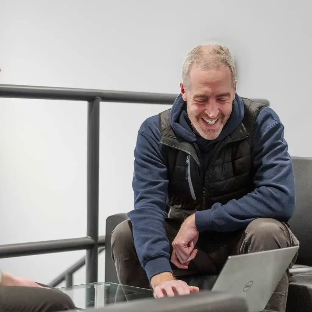 Darren Salisbury on a chair laughing and looking at a laptop