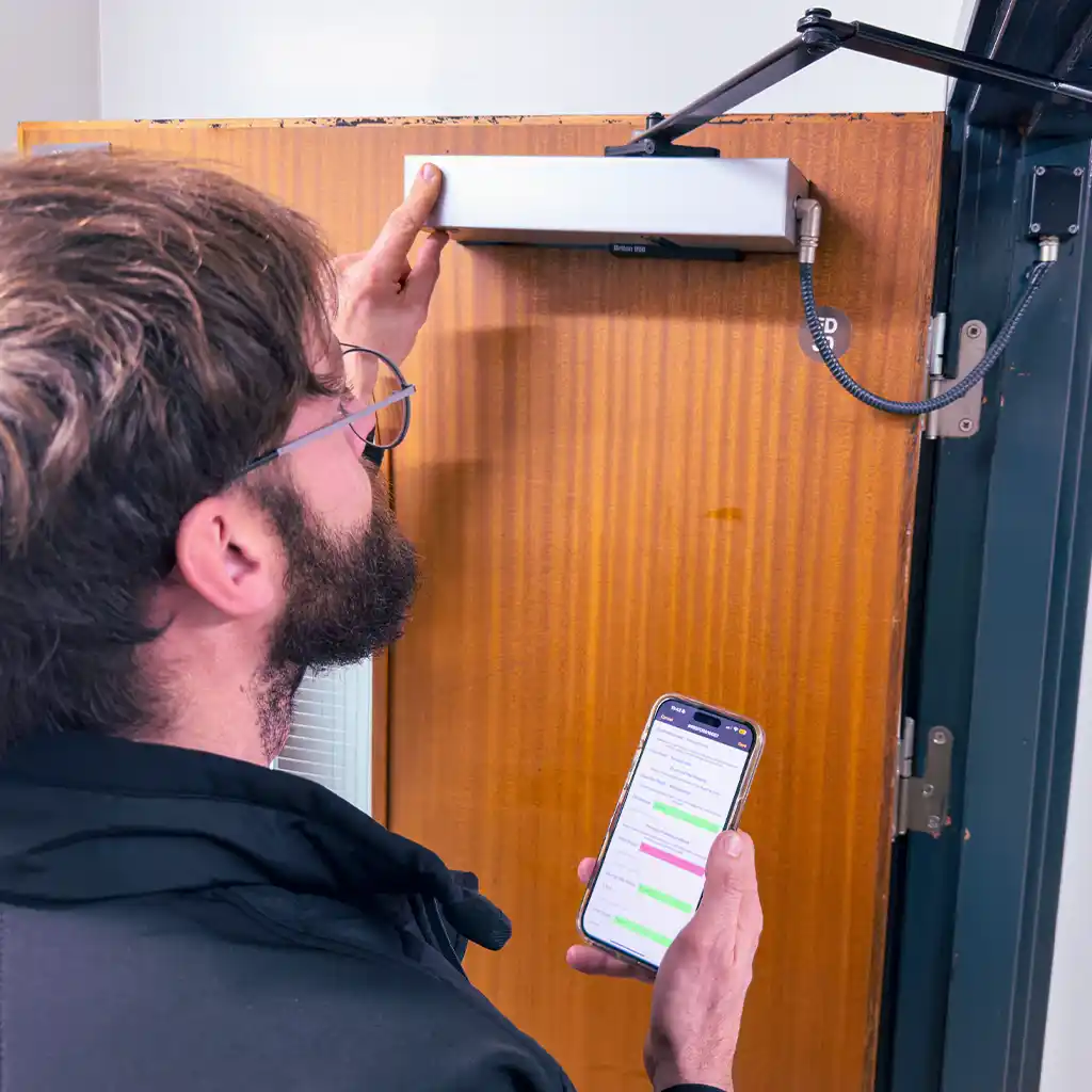 fire door inspector assessing an electronic closer on a fire door